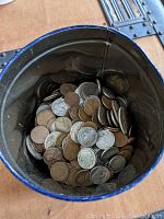 View into metal coffee can showing mixed wheat pennies and silver coins