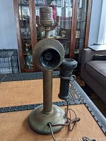 Front view of antique brass candlestick telephone lamp showing mouthpiece, receiver, and wiring.