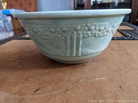 Side view of Homer Laughlin ceramic bowl showing embossed orange tree design on light blue-green glaze.