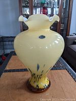 Front view of large yellow Murano glass vase with blue accents and wavy rim. Original Murano sticker visible.