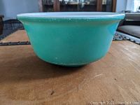 Side view of medium Hazel Atlas green mixing bowl showing smooth exterior finish and white interior rim.