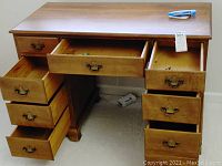 Full front view of wooden desk with drawers open showing inside drawer space and brass handles