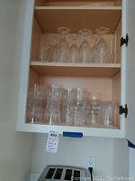 Glass cabinet shelf with 4 upside-down champagne flutes and assorted water glasses