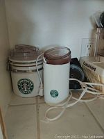 Photo showing Starbucks branded coffee bean grinder and a Starbucks branded container with lid.