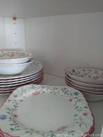 Multiple stacked plates and bowls with floral designs and scalloped edges