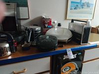 Photo showing various kitchen appliances including coffee maker, waffle maker, roasting pan, and popcorn maker.