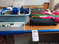 Wide shot of craft and model paint supplies, umbrellas, and banners on blue table