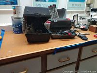 Overall photo showing stapler, level, Dremel in a black case, and other tools on countertop.