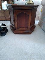 Hexagonal wood table with closed doors viewed from front, showing wood grain finish and brass hardware.