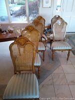 Overview photo showing all six dining chairs arranged in two rows, highlighting the cane backs and light blue striped seats.