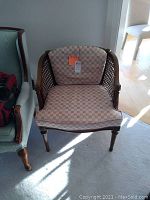 Front view of white patterned armchair with wood frame and cane sides, showing overall condition and design.