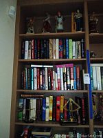 Full bookshelf showing top figurines, books and brass instruments below