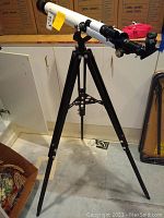 Full view of the black and white telescope mounted on an adjustable black tripod stand.