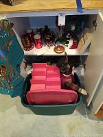 Wide view of holiday decor items on shelves including candles, figurines, red storage boxes, and pine cone decorations.