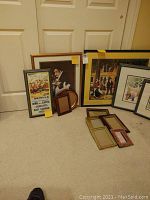 Photo showing all framed artworks and empty frames grouped on the floor against white doors and beige wall.