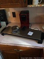 Wide view of electric hot plate, Mr Coffee Keurig coffee maker and boxed permanent filter on kitchen counter