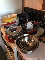 Photo showing various bakeware including Bundt pans, loaf pans, ring pans, bake sheets, and mixing bowls set on stove and kitchen countertop.