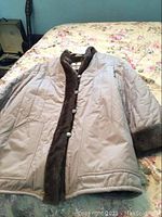 Full view of the beige ladies rainmaster jacket laid flat, showing the brown fur trim along the front opening and collar area.