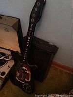 Black guitar amplifier Crate G10XL with guitar body part visible, standing on carpeted floor near wall and turntable.