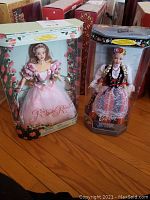 Two boxed Barbie dolls displayed side by side on hardwood floor