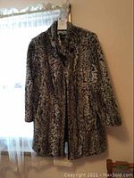 Full view of the faux fur jacket showing leopard print pattern and mid-thigh length with long sleeves.