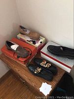 Four pairs of ladies size 7 shoes, all new in box, displayed on wooden cabinet.