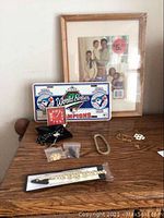 Image showing assorted jewelry including bracelets, earrings, a rosary, a decorative tin, and a framed family photo.