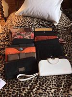 Photo showing multiple wallets including black, white, orange studded and floral designs on leopard print background.