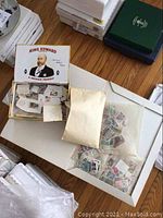 Overview photo of King Edward tobacco box filled with assorted stamps including loose stamps and envelopes with stamps.