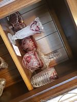 Crystal glass pieces including red accented bowls, vases, and basket inside display shelf