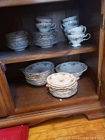 Bowls and cups stacked on upper shelf, plates and bowls on lower shelf