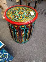 Full view of the octagonal round Moroccan wood table showing the height and colorful painted design on sides and top.