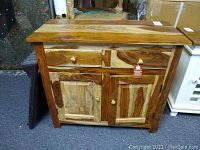 Front view of handcrafted solid wood buffet showing two drawers over two-door cabinet with brass knobs.