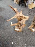 Full view of the driftwood sculpture showing its natural texture, shape and base on carpeted floor.
