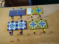Set of four double ceramic tile coat hooks on table showing all four designs.