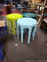Photo showing three octagonal composite Moroccan tables in light blue, bright green, and dark green colors grouped together on carpet.