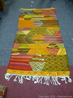 Full view of the colorful handwoven Berber tribal wool rug laid out flat, showing geometric patterns and tassels.