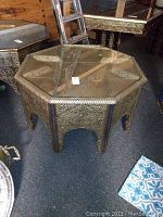 Full view of the octagonal Moroccan style table showing the intricate metal overlay and glass top.