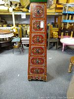 Full view of the six drawer Moroccan storage cabinet showing trapezoidal shape and decorative painted surfaces.