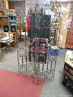 Front view of the Moroccan wrought iron room divider showing all three panels with intricate scrollwork and pointed arch tops.