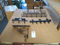 Lot of five wrought iron items placed on cardboard box for display in room with cardboard boxes