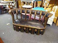 Full view of Moroccan loveseat showing curved backrest and seat, leather upholstery with metal stud accents, and ornate wood base with painted floral designs.