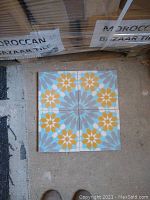 Four cement mosaic tiles arranged to show pattern: yellow flower with eight petals, turquoise and blue starburst background.