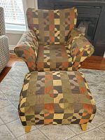 Front view of upholstered armchair and matching ottoman showing geometric fabric pattern and wooden legs