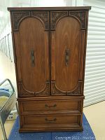 Front view of armoire showing carved arched doors and lower drawers