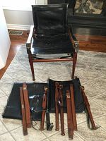 One assembled safari chair displayed behind disassembled components and leather slings for the second chair
