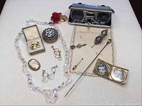 Full lot with necklace, earrings, pins, opera glasses, photo frame and trinket box shown from a distance