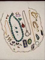 Full assortment of necklaces, bracelets, earrings, brooches, pendants, and rings on beige fabric