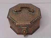 Front and top view of octagonal copper embossed betel nut box showing floral patterns, handle, and locking clasp.