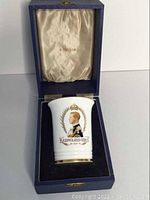 Blue leatherette hinged presentation case open, showing beaker nestled in velvet base